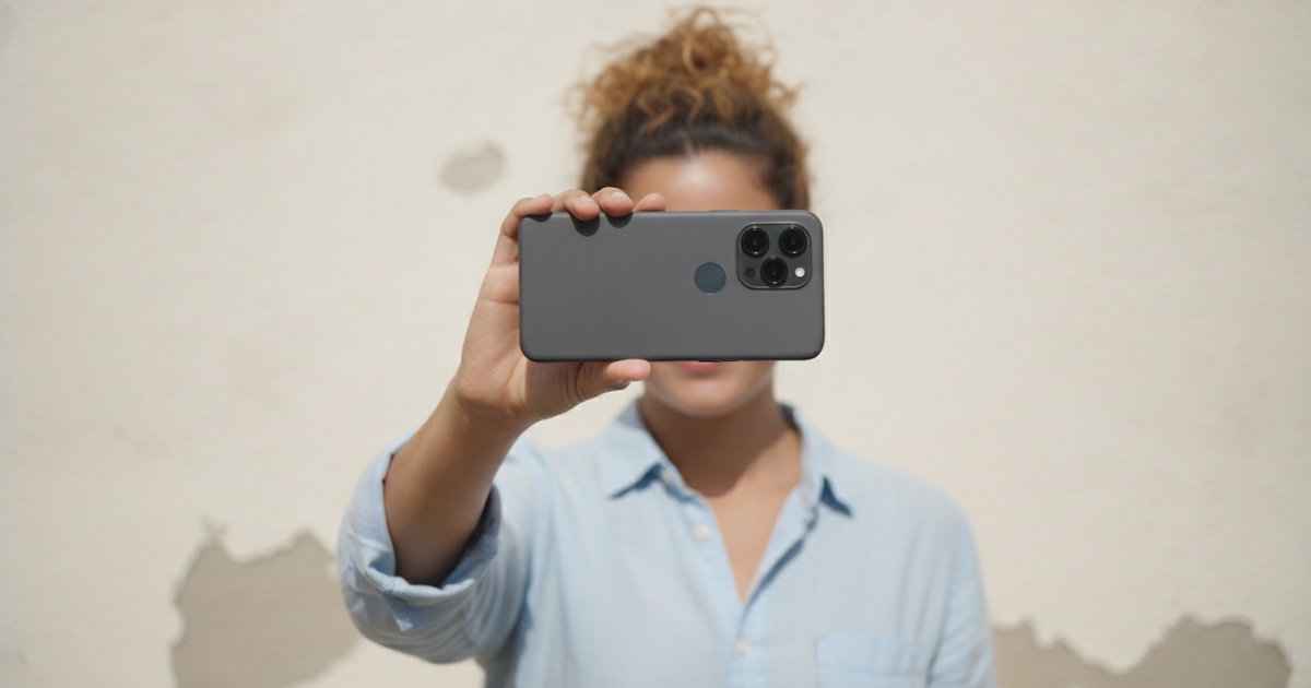 Person taking a self-photo against a plain wall